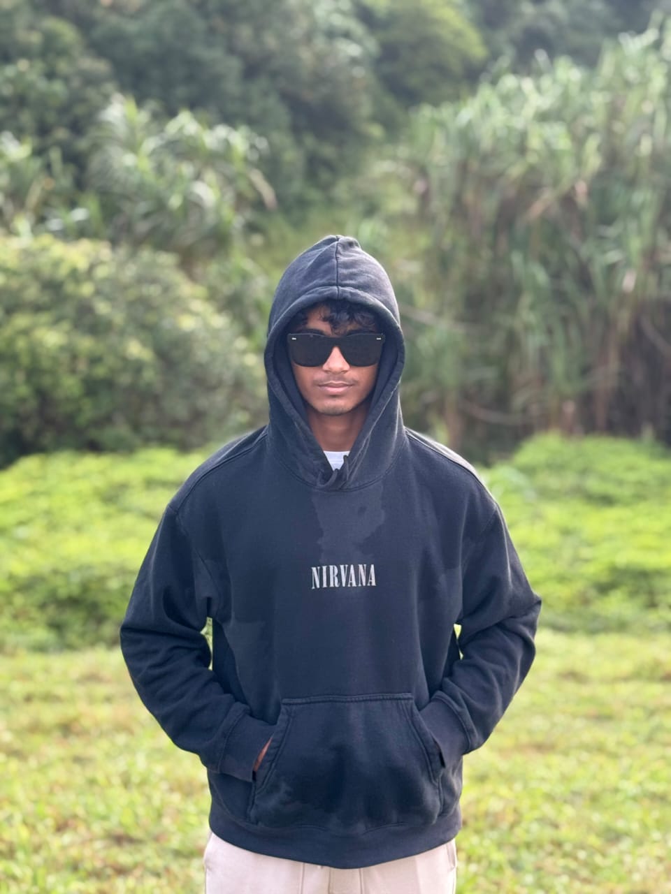 Dharane wearing sunglasses and a dark hooded sweatshirt outdoors